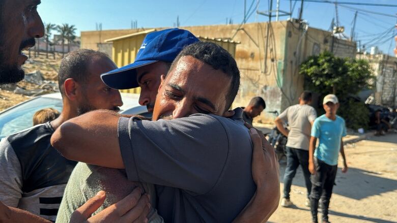 A man cries as he embraces another man on a street.