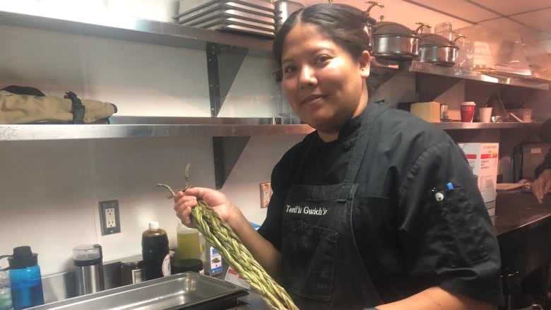 smiling woman in chef uniform holds up sweetgrass