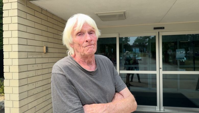 A profile shot of an elderly man outside a sliding door.