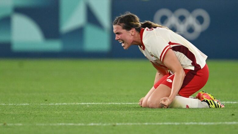 A soccer player screams while on the ground.