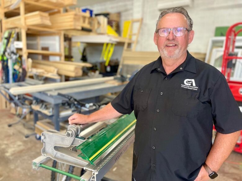 A man stands in work shop and smiles 