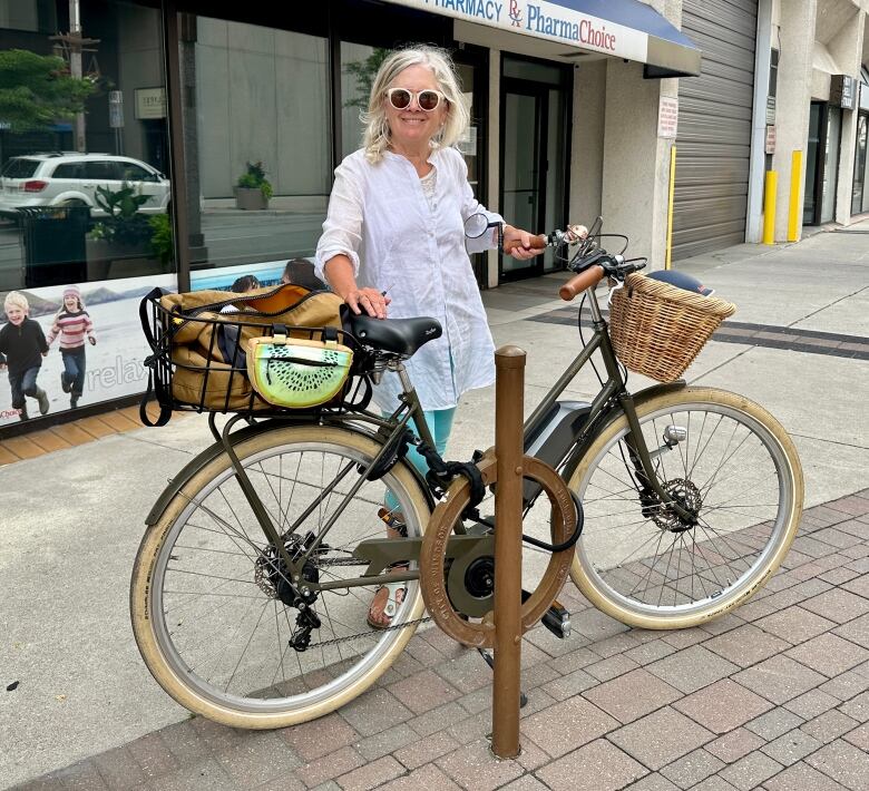 A woman with a bicycle locked to a rack.