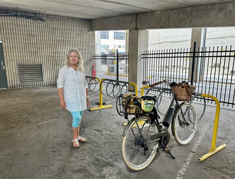 A woman next to a bike rack inside a parking garage.