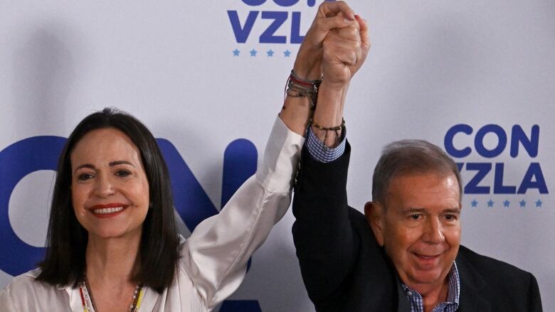 Venezuelan opposition leader Maria Corina Machado hold hands up with opposition presidential candidate Edmundo Gonzalez Urrutia in Caracas on July 29, 2024, a day after the Venezuelan presidential election.