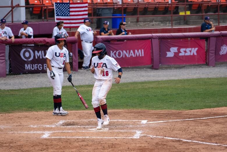 A baseball player crosses home plate.