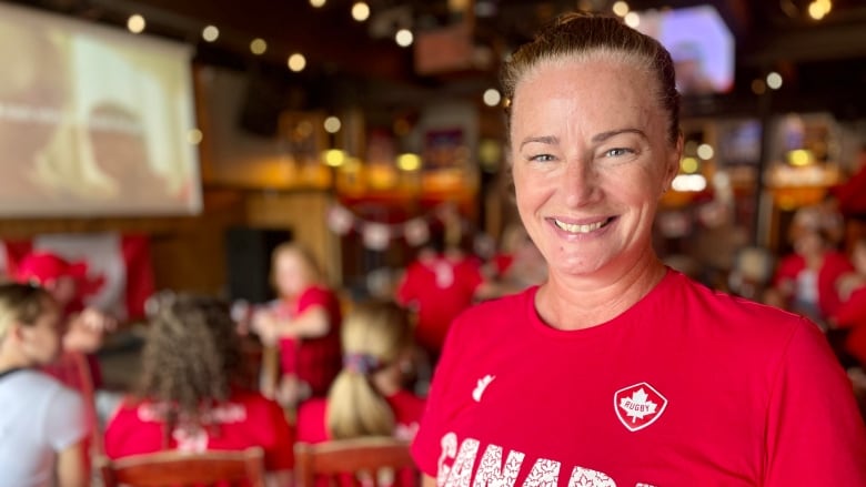 A woman smiles and wears a read team canada shirt. 