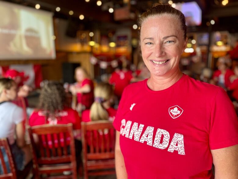 A woman smiles and wears a read team canada shirt. 