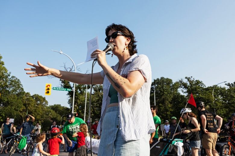 A person holds a microphone as they speak at a bike rally. 