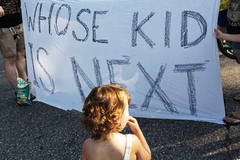 A child stands in front of a sign that says 