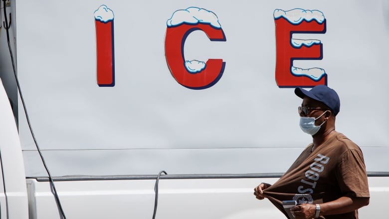 A man walks in front of an ice truck.