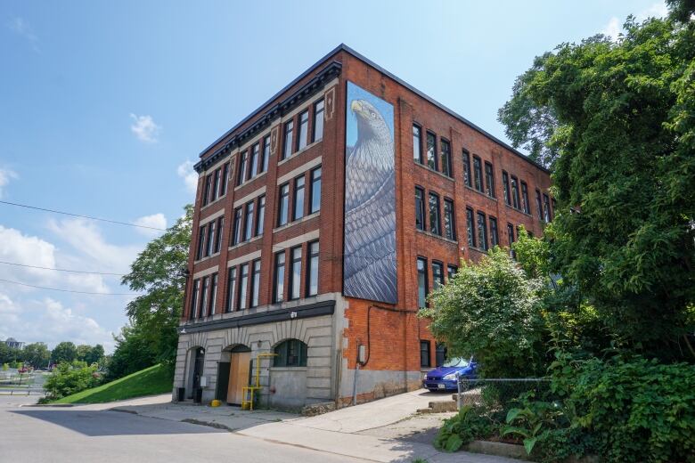 A three-story red brick building, with an eagle mural to the side.