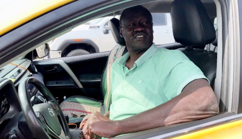 A man in the driver's seat of a yellow vehicle.