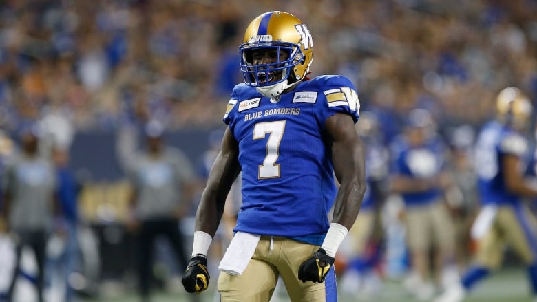 A player in a Blue Bombers uniform shouts with fists clenched at his side.