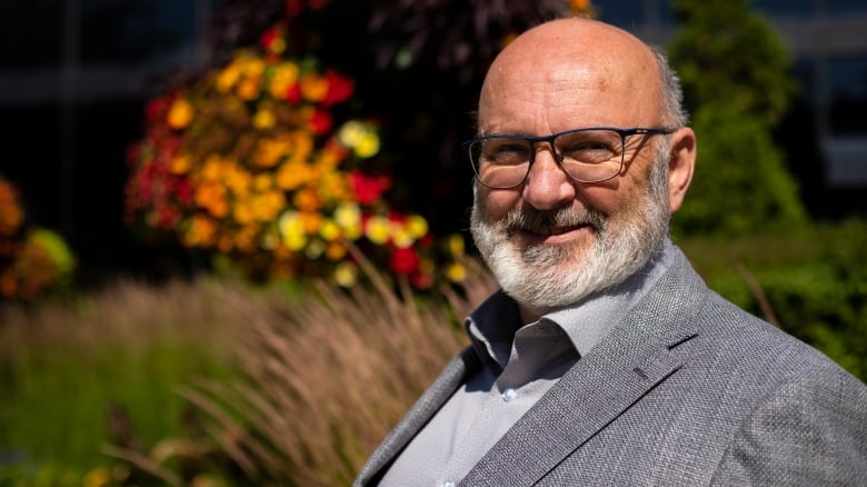 A man stands smiling by flowers.