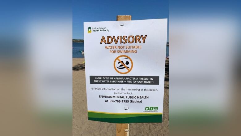 Photo shows a sign planted in the sand at Regina Beach. It says 