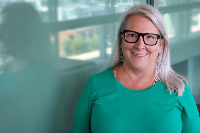 Headshot of a woman with glasses and a green shirt.