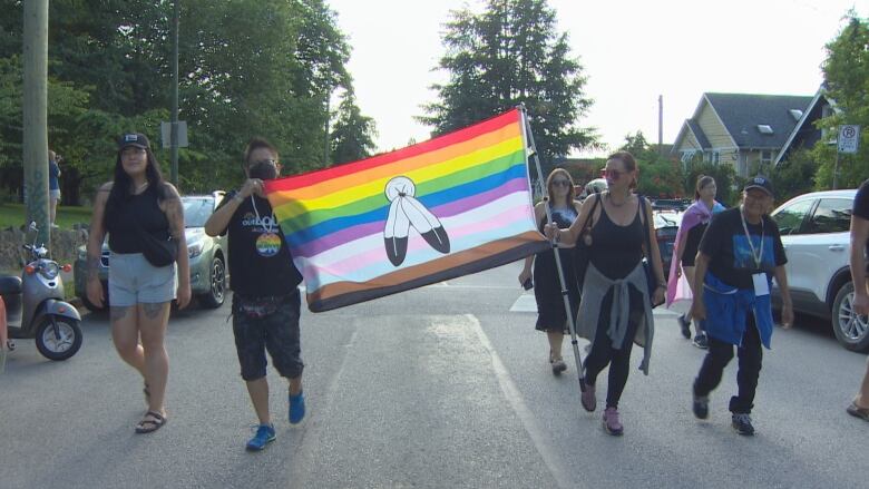 Vancouver Pride Trans March's attendees walked through a street near Commercial Drive, raising a flag.