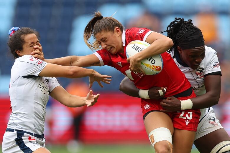 Shalaya Valenzuela runs through opposing team with the rugby ball. 