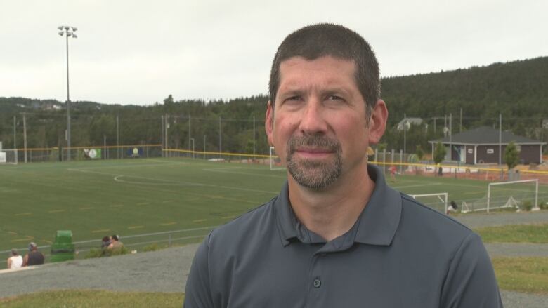 Man smiles with soccer field in background 