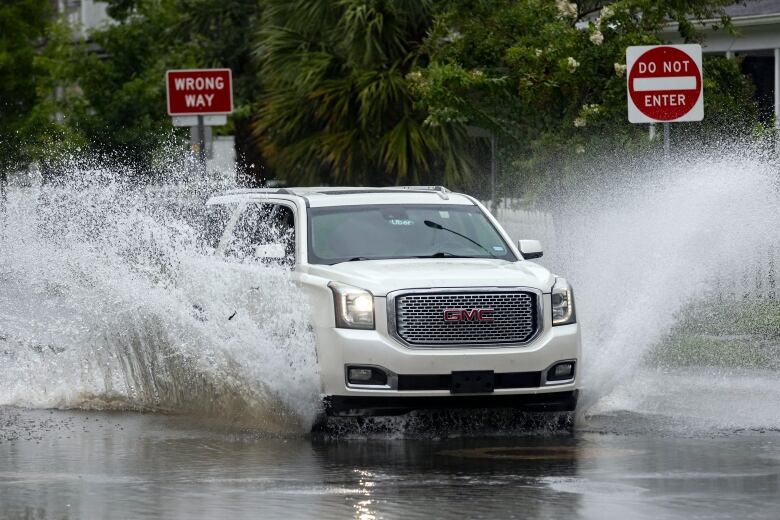 An SUV plows through a flooded street after heavy rain from tropical storm Debby.