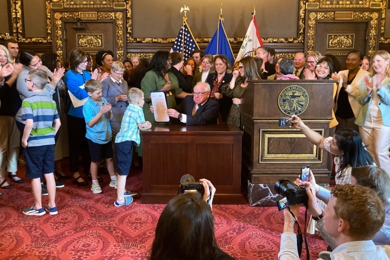 Democratic Minnesota Gov. Tim Walz jokes with kids as he shows off a bill he signed.