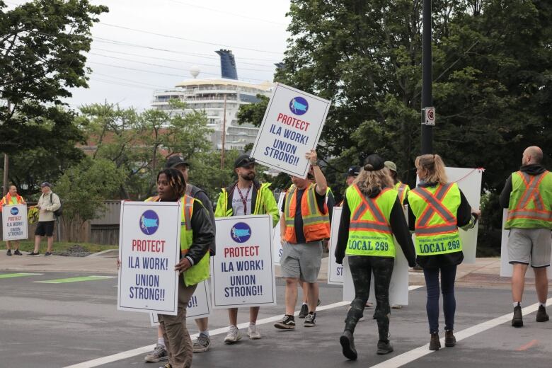 People cross a crosswalk holding signs saying 