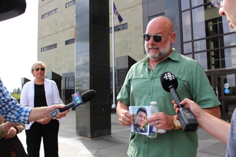 Rick Boudreau holds up a photo of Max Boudreau.