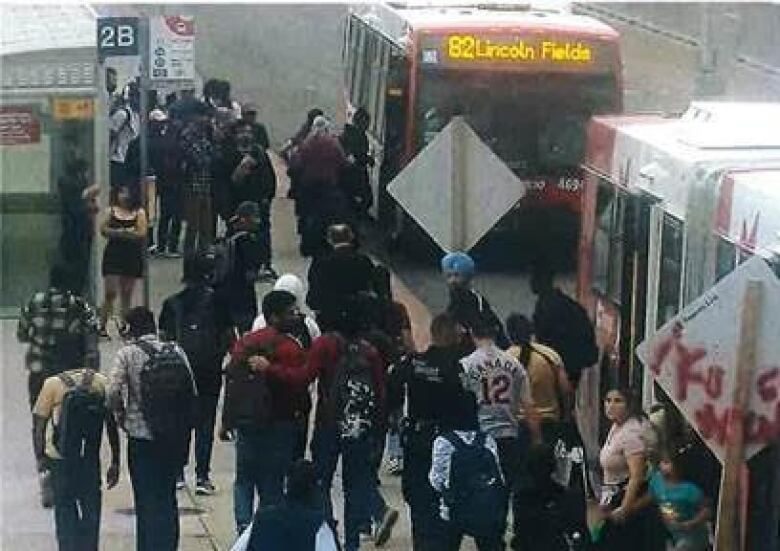 A crowd of people outside of a city bus. 