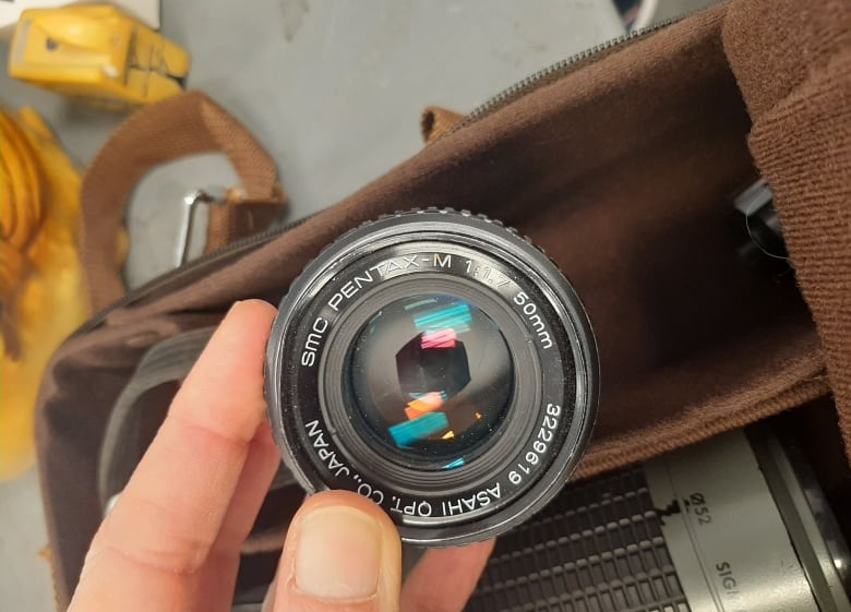 A hand holds a camera lens.