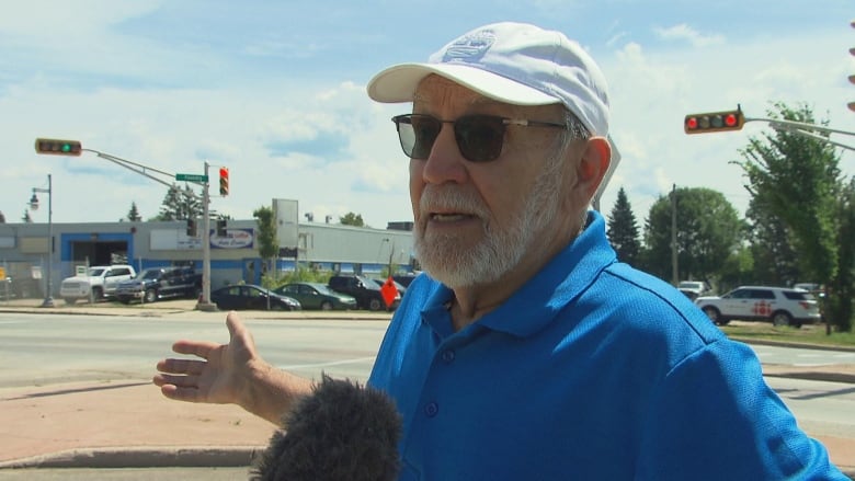 A man in a blue shirt stands on a street corner in Moncton.