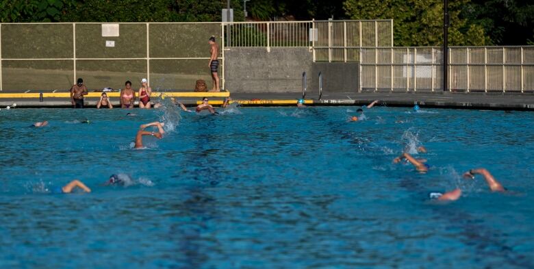 A public pool is photographed with people swimming. 