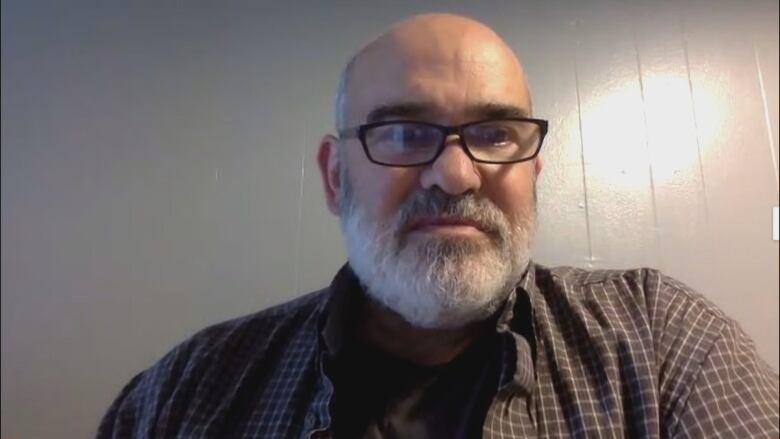 Bald man with grey beard and black-rimmed glasses.