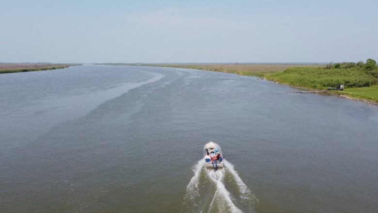 Drone shot of boat heading down wide river