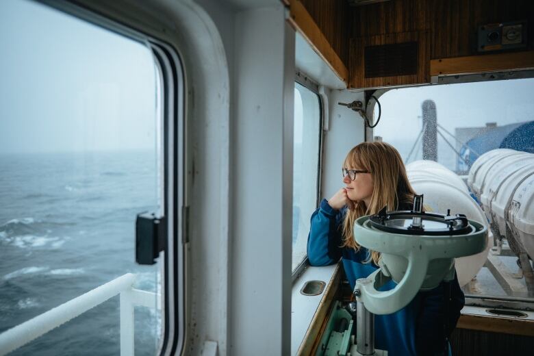 Woman with light brown hair gazing out window of boat