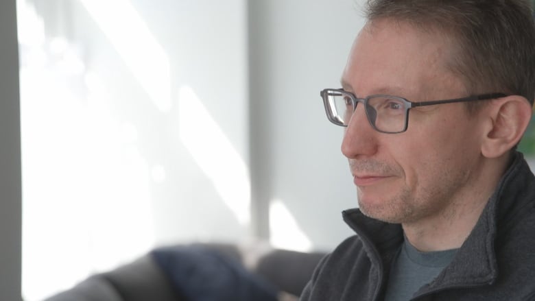 Close up shot of a man wearing glasses looking out into the distance. 