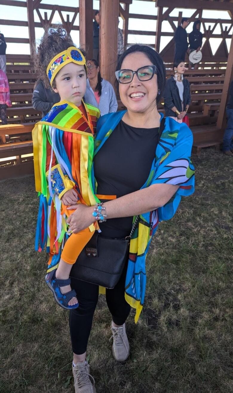 A mother holding her son, smiling for the camera. 