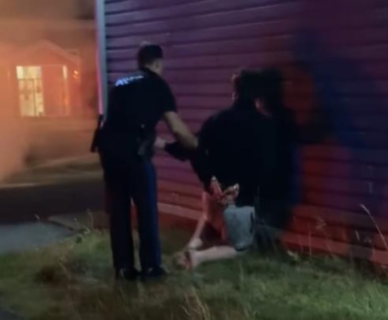 A man on his knees in handcuffs from behind