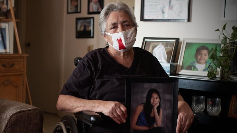 An elderly woman holds a portrait