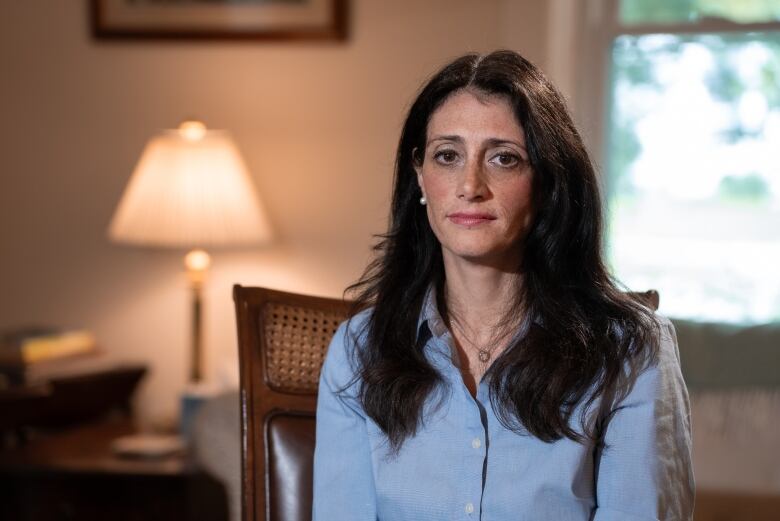 Woman in chair looks into camera.