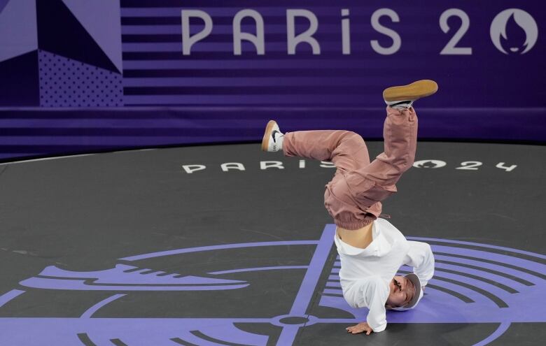 A woman contorts her body as she holds herself up upside down while dancing.