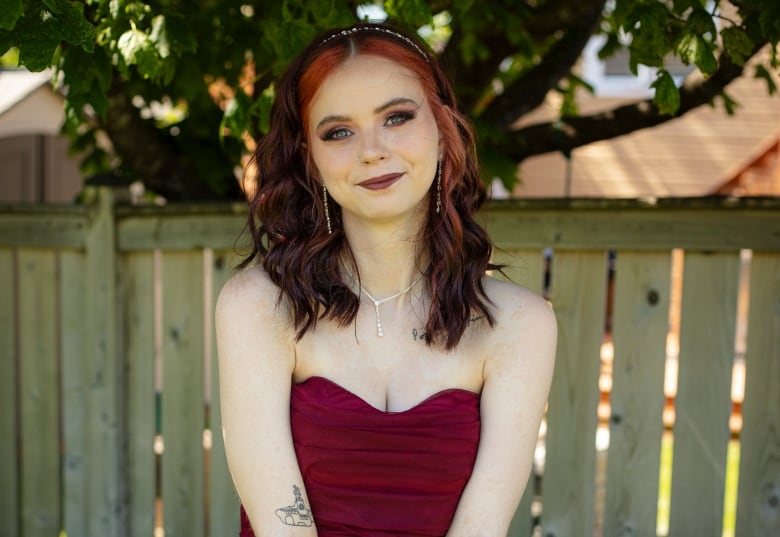 Young woman with red and black hair, in red dress.