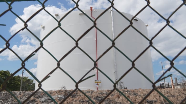 a large white holding tank behind a chainlink fence