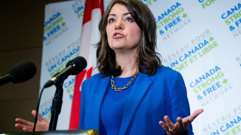 A woman gestures at a lectern.