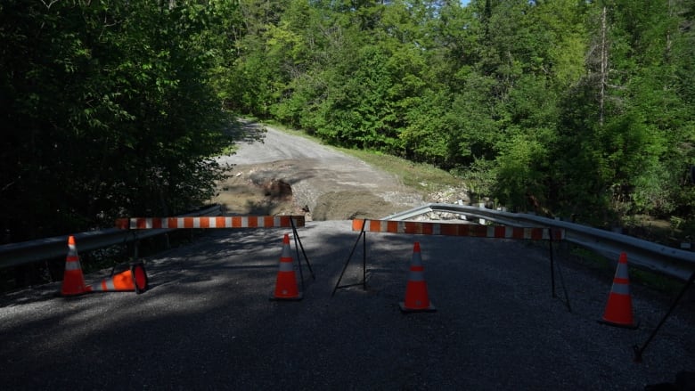 A road crumbles a few metres away from the photographer, with orange and white barricades blocking it off to traffic