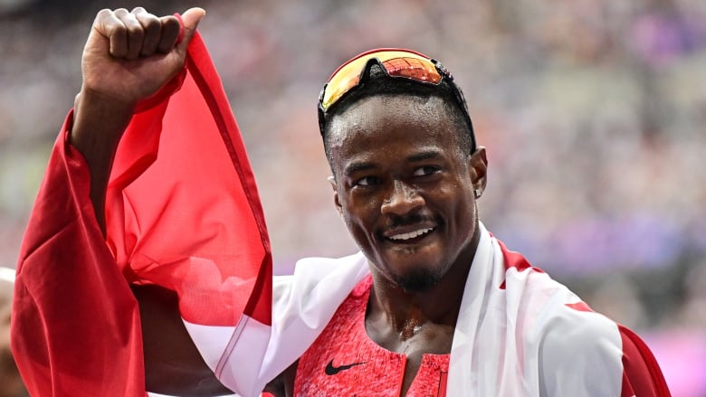 A man draped in a Canadian flag pumps his fist in the air.