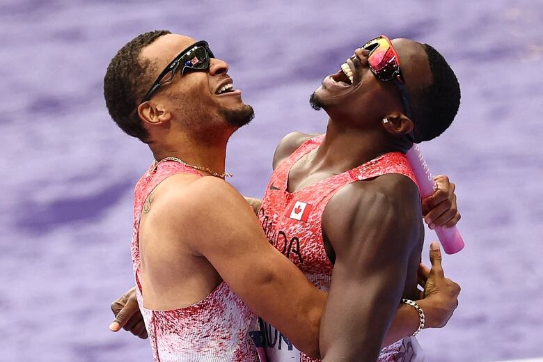 Two sprinters embrace in celebration.