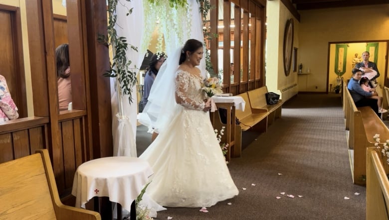 A bride in a wedding dress walks down the aisle.