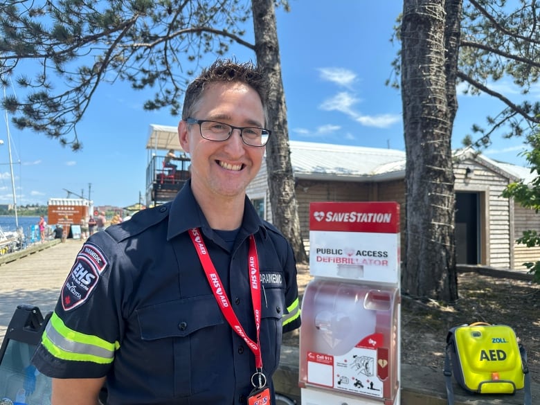 a paramedic smiles at the camera in front of a debilator station. 