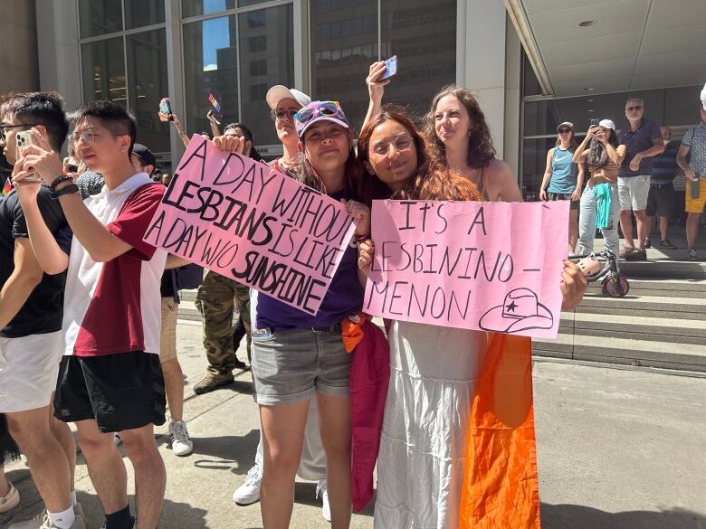 Two young girls holding up pink signs that read, 