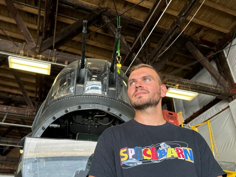 A man stands under a WW2 plane gun turret.